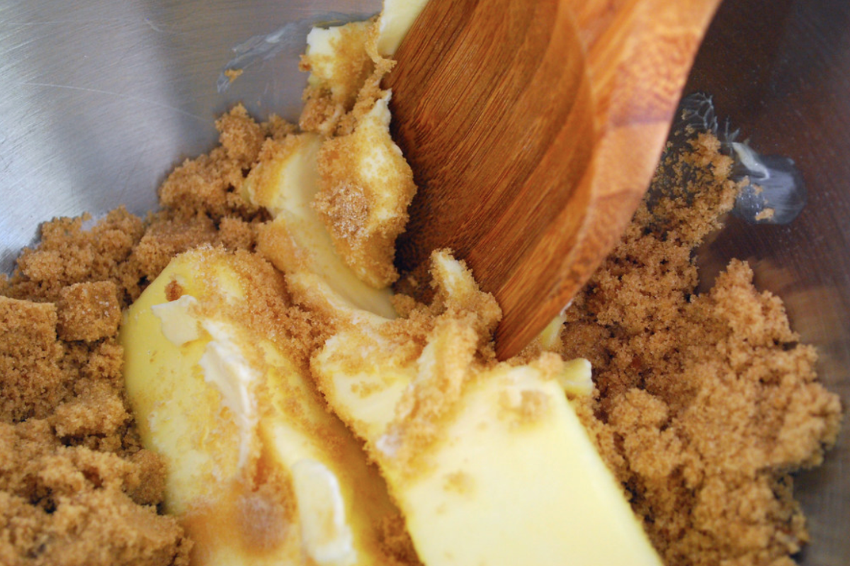 An image of brown sugar being mixed with a stick of butter. 
